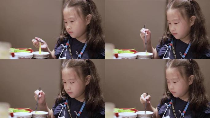 可爱的亚洲小女孩用筷子打鸡蛋