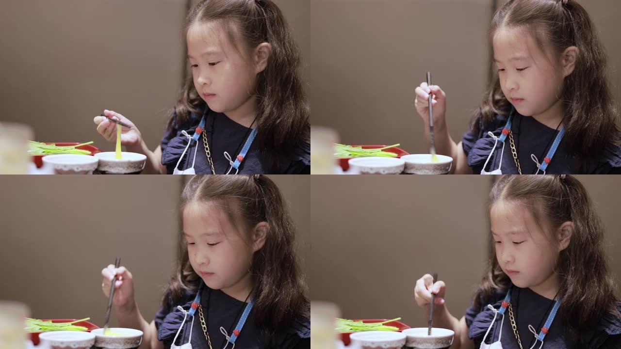 可爱的亚洲小女孩用筷子打鸡蛋