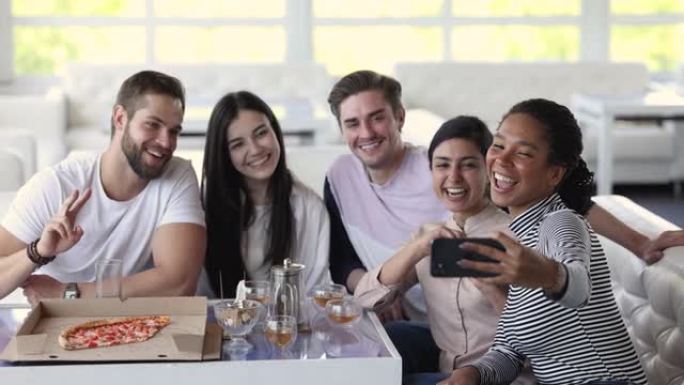 快乐的多民族朋友在披萨店聚集的手机上自拍