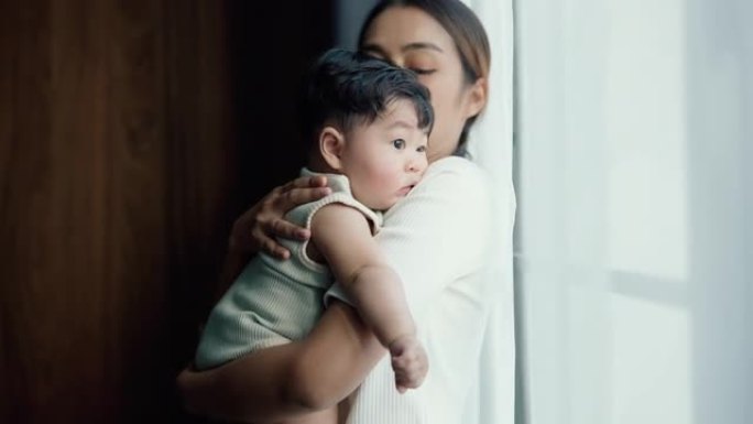 年轻的亚洲母亲抱着她可爱的男婴