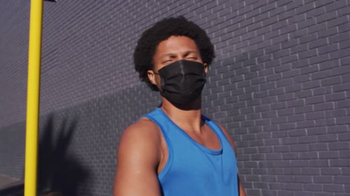 适合非裔美国男子在城市锻炼时戴着口罩，在街上伸展