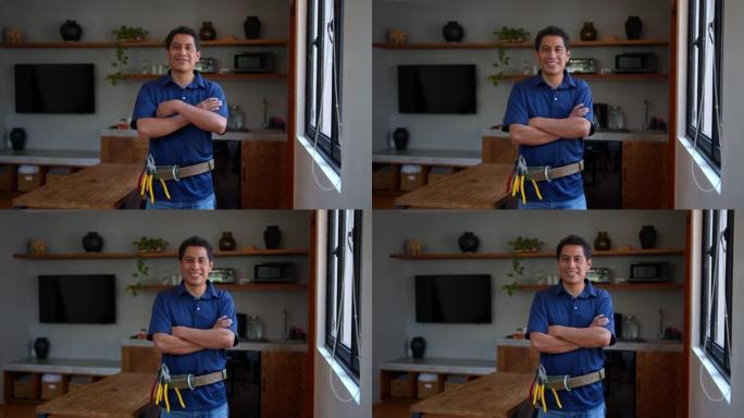 快乐的拉丁美洲电工在房子里工作，双臂交叉看着相机微笑