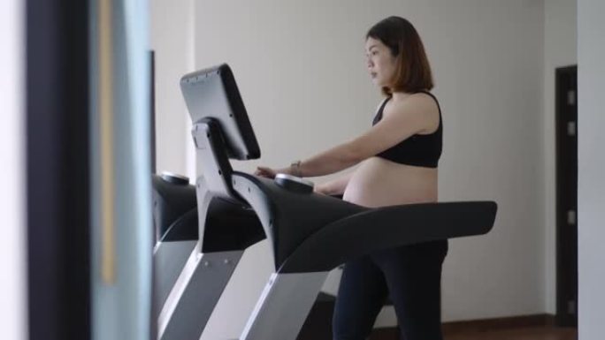孕妇在健身室锻炼，在跑步机上行走，身体健康和有氧运动