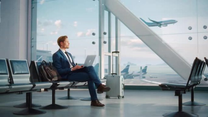 现代机场航站楼: 英俊的商人在等待飞行时在笔记本电脑上工作。一名男子坐在大型航空公司枢纽的登机休息室