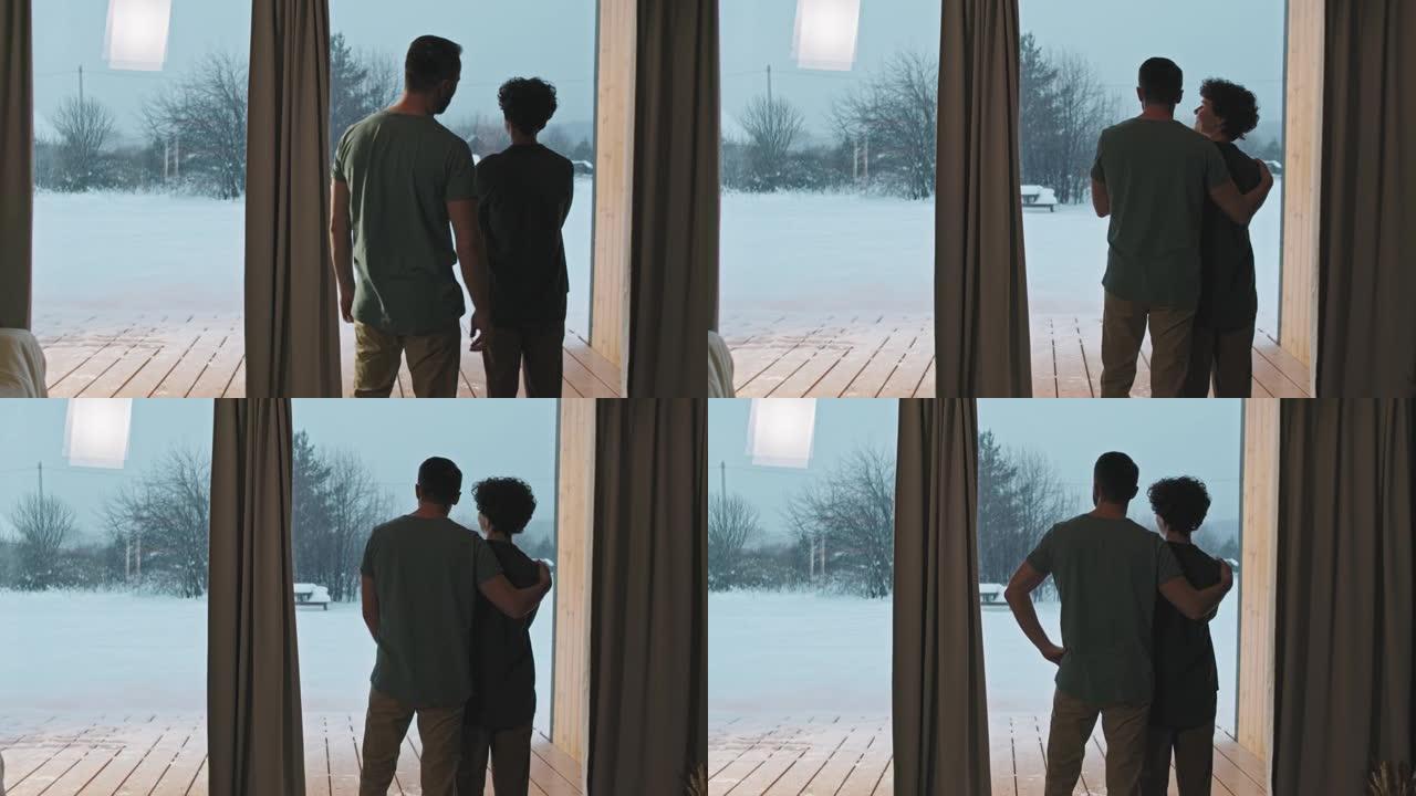 夫妇通过全景窗口观看降雪