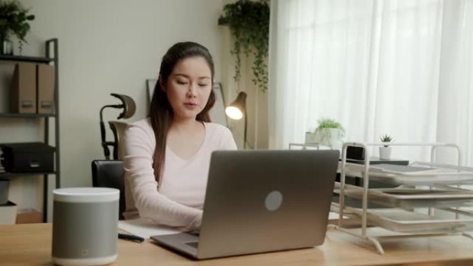 智能扬声器数字助理技术。女人在笔记本电脑上工作时向智能扬声器设备提问。