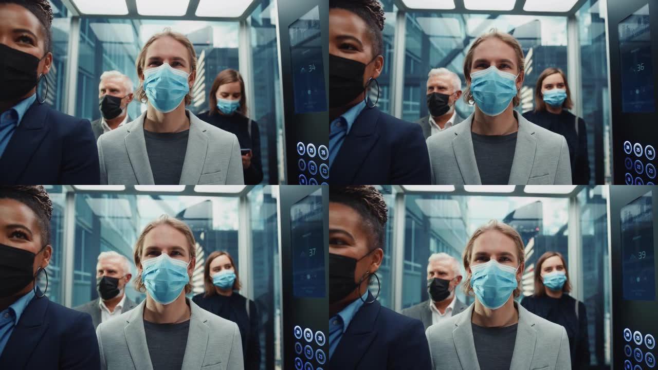 四个戴着防护口罩的多种族国际人士乘坐玻璃电梯在现代商务中心上班。医疗保健、新型冠状病毒肺炎大流行和疫