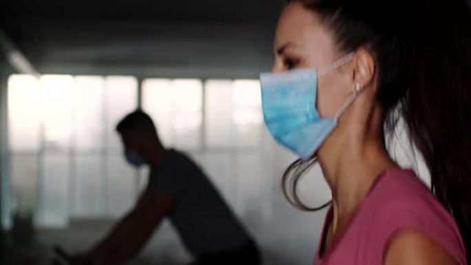 在健身俱乐部的跑步机上跑步时戴着口罩的SLO MO女人