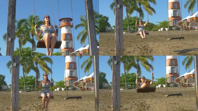 慢动作视频: 微笑的年轻女子在海滩秋千上享受暑假