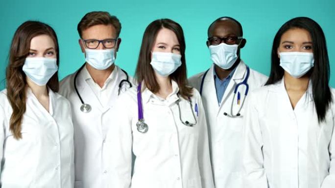 医生在室内戴医用口罩。美丽的国际团队年轻医药工作者保健尊重。一群穿着白大褂的专业成功医务人员在慢动作