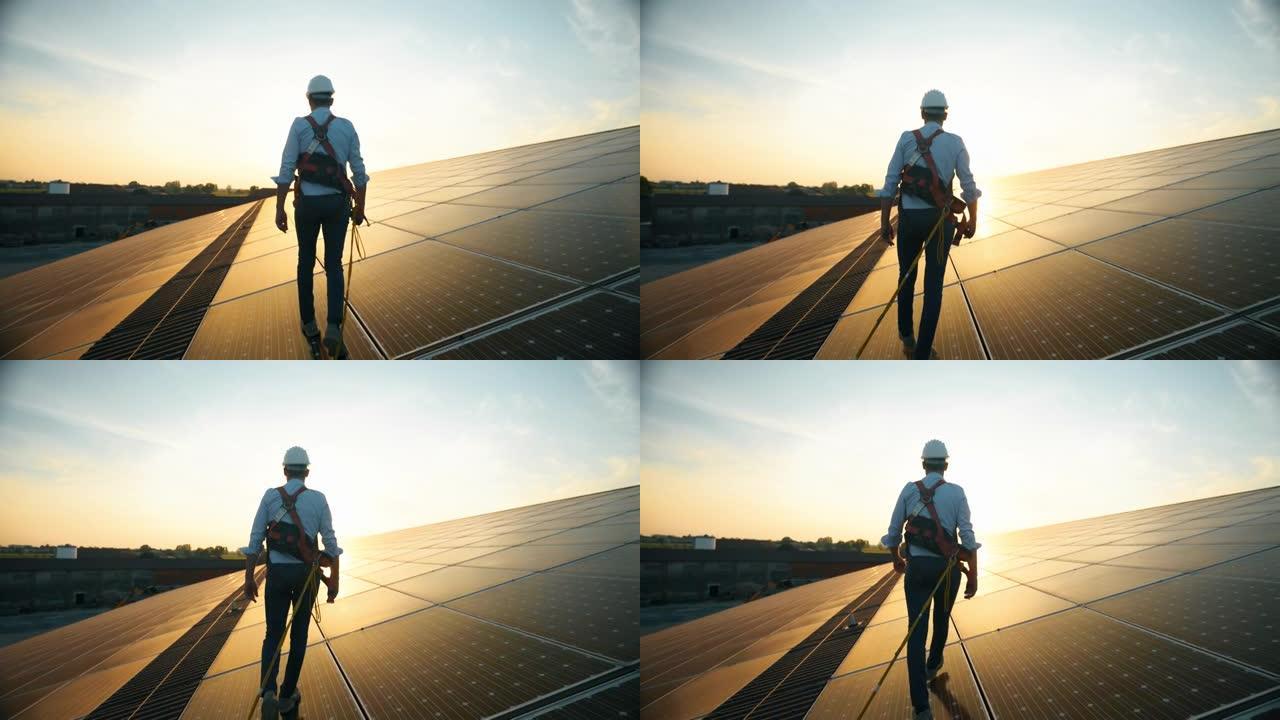 穿着制服的维修协助技术工人正在检查日落时屋顶上光伏太阳能电池板的运行和效率性能。前视图