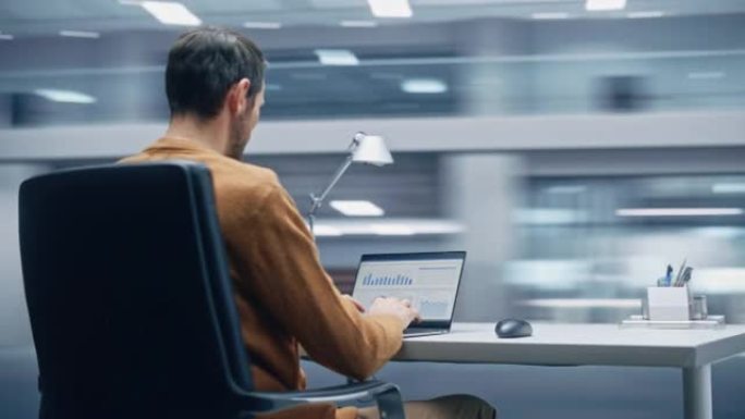 360度现代办公室:英俊的商人坐在办公桌前用笔记本电脑工作。从事大数据电子商务分析的人。精力充沛的快