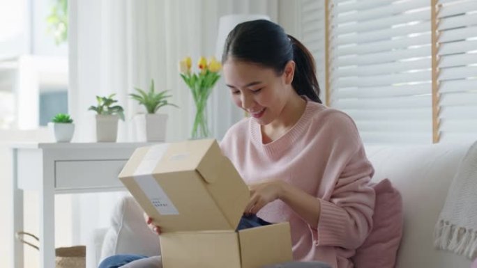 亚洲女人快乐打开快递箱在家网上购物。