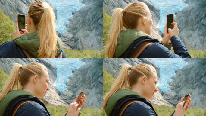 4k视频片段，一名年轻女子站着并用手机拍摄Briksdal冰川