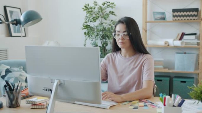 年轻的亚洲黑发设计师在家里使用电脑工作的肖像
