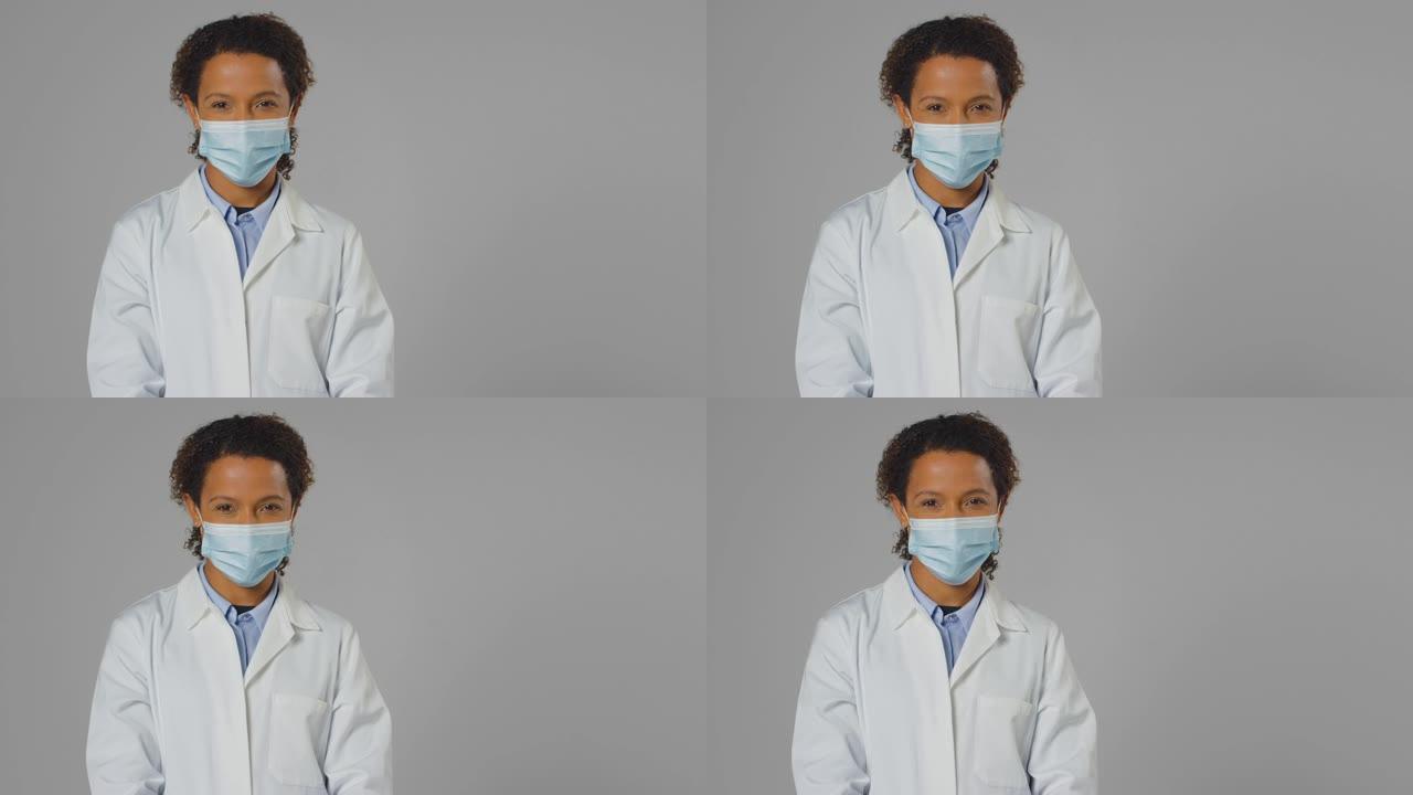 微笑的女医生或实验室工作人员穿着白色外套戴着口罩的工作室肖像