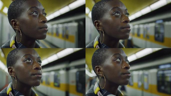 年轻时尚的黑人妇女站在地铁站，环顾四周的电影镜头。一名非裔美国女性在等待公共交通时思考和环顾四周