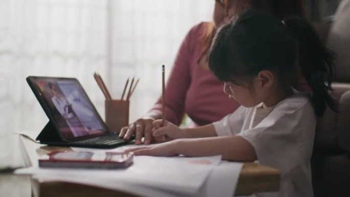 通过数字远程互联网会议从学校老师那里获得的年轻亚洲母女在线课程