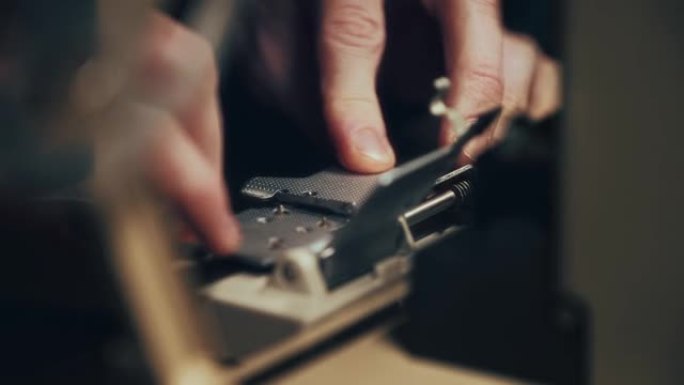 一名男子的手的特写镜头在一个特殊的印刷机上铺设了一个8毫米的薄膜，用于粘合单个片。