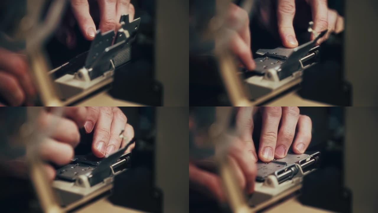 一名男子的手的特写镜头在一个特殊的印刷机上铺设了一个8毫米的薄膜，用于粘合单个片。
