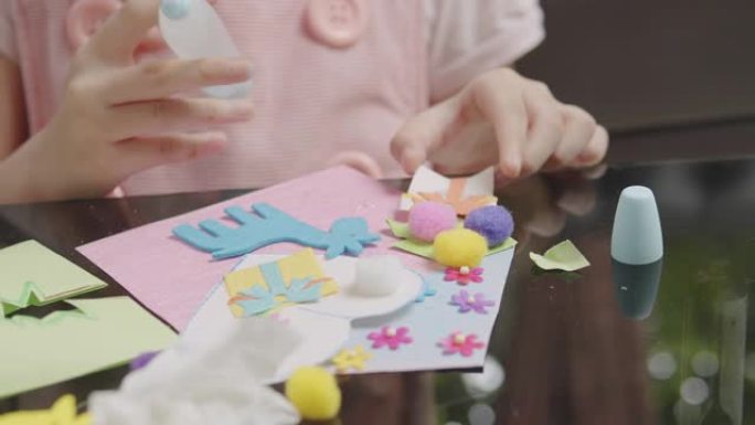 亚洲女孩在家时在客厅剪纸并制作手工艺品。他们使用彩纸，剪刀和胶水在纸上创作艺术作品，以形成她的想象力