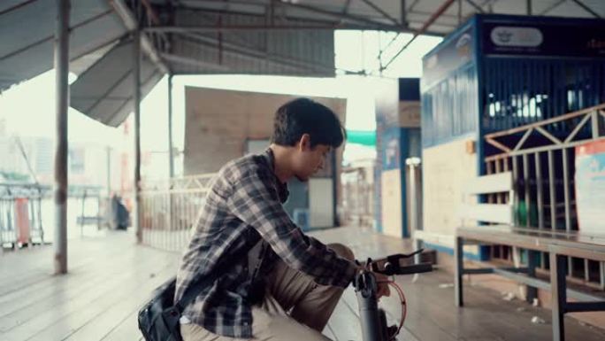 年轻人带着他值得信赖的踏板车在曼谷旅行。