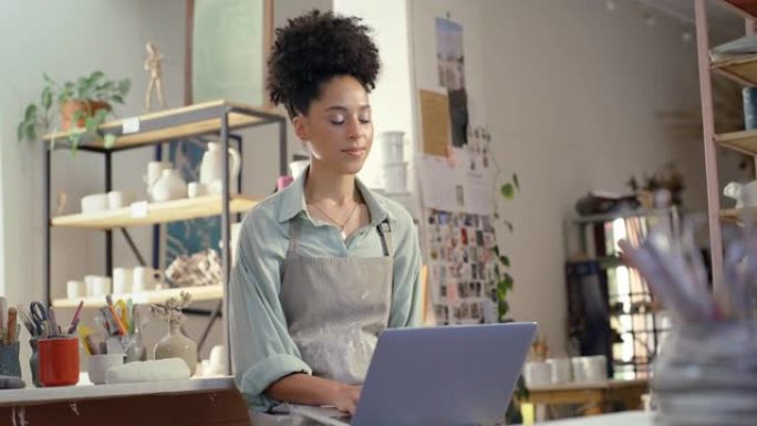 女人，小企业主，在陶瓷工作室从事笔记本电脑工作，在车间计划电子商务销售或网站。年轻的陶器艺术家，设计