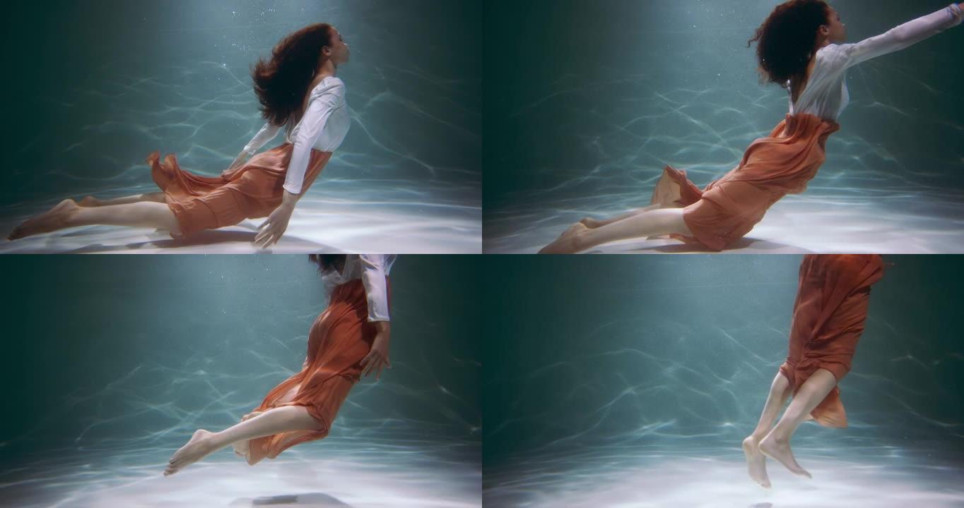 美丽的电影视角，年轻美丽的混血女人穿着便服摆姿势，漂浮在水下慢动作。