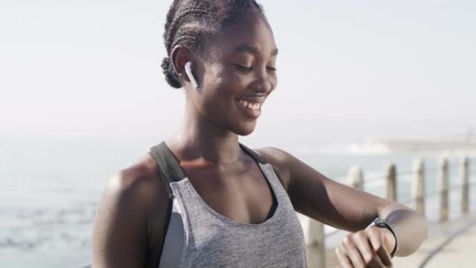 4k视频片段，一名年轻女子戴着earpods并在外出跑步时使用智能手表