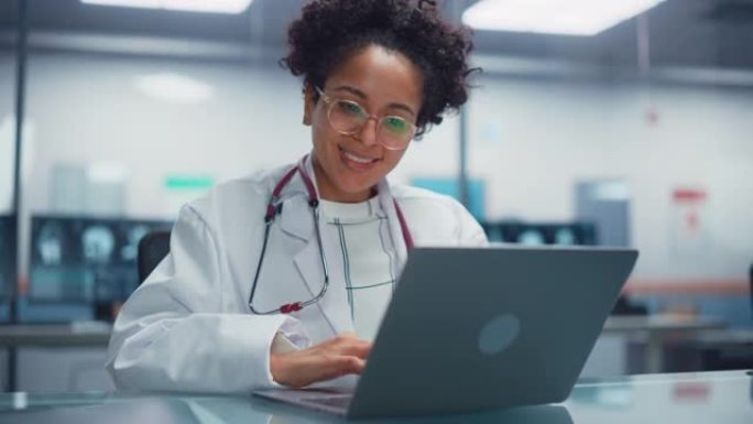 医院医生办公室: 年轻有前途的黑人医生的肖像在笔记本电脑上工作。穿着白色实验室外套的女性医疗专业人员