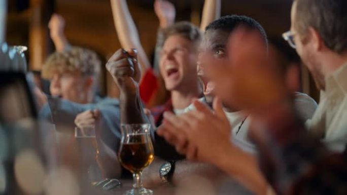 一群多民族的朋友在体育酒吧看电视直播的足球比赛。兴奋的球迷欢呼和喊叫。当球队进球并赢得足球世界杯时，
