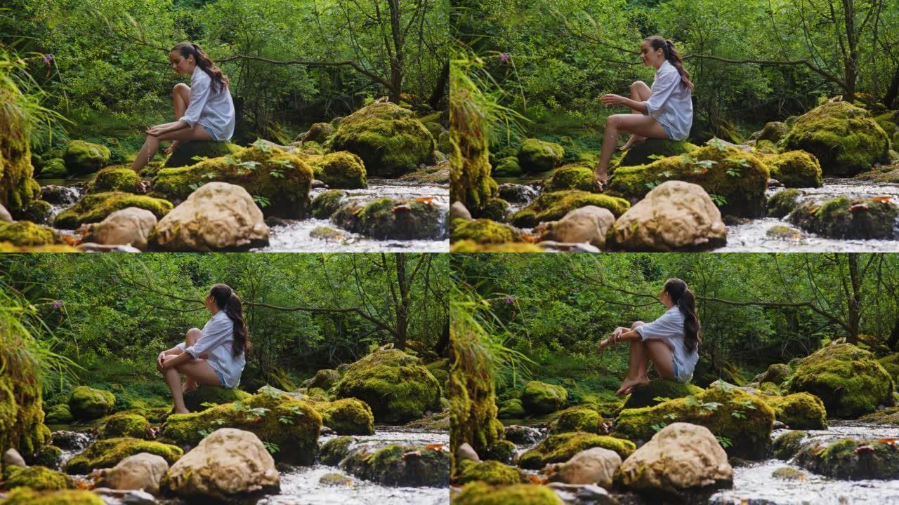 SLO MO年轻女子用手从森林中的溪流中捞水
