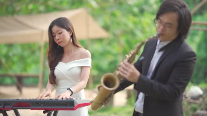 亚洲中国夫妇萨克斯管键盘演奏家乐队在农村地区表演正装练习