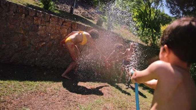 母亲和孩子被男孩用水管溅水