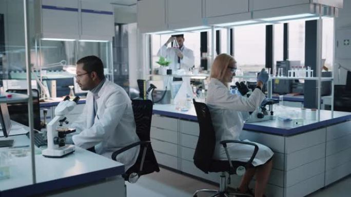 医学研究科学家团队在显微镜，试管，微量移液器的帮助下进行实验，并在计算机上写下分析结果。现代生物应用