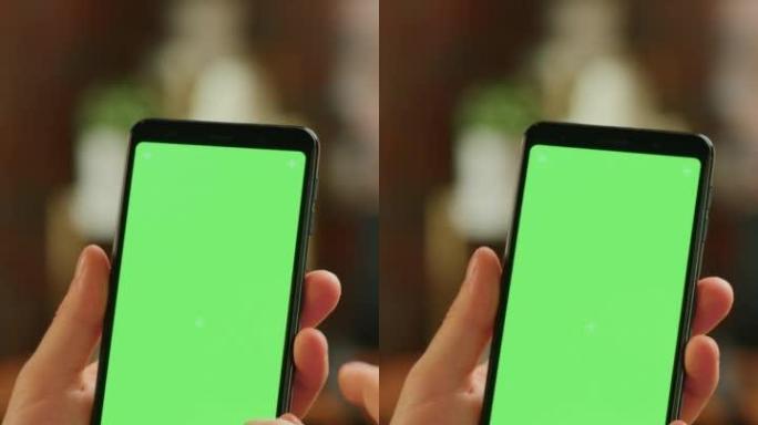 垂直屏幕: 带有绿屏模拟显示的智能手机上的手动滚动供稿。在家里休息并在移动设备上查看社交媒体的人。特