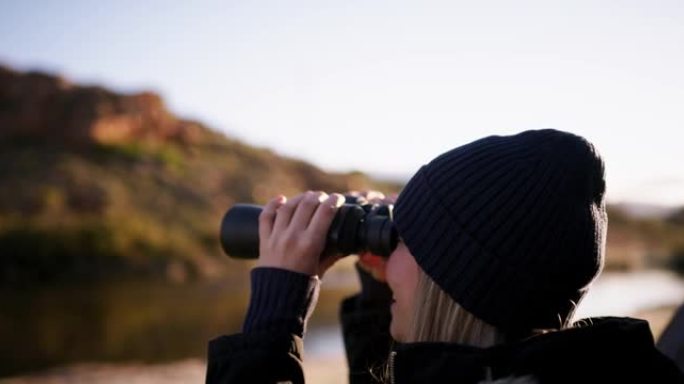 一名年轻女子在营地中透过双筒望远镜观看的录像