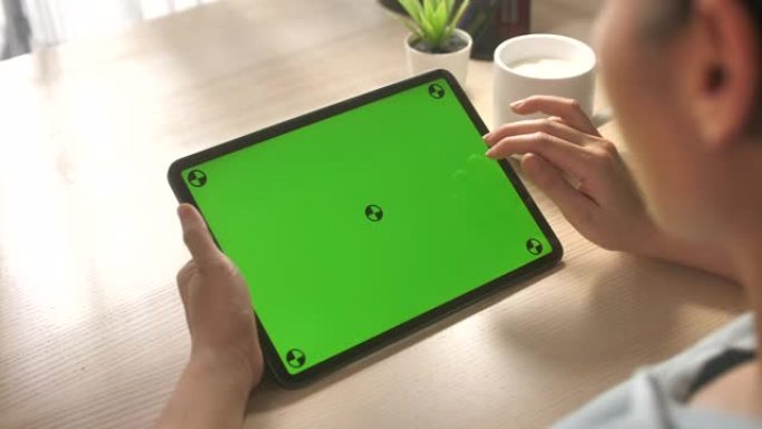 在家里的办公桌上使用带有绿色屏幕的数字平板电脑的特写手