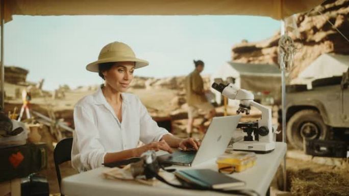考古挖掘地点: 美丽的女性考古学家进行研究，使用笔记本电脑，用显微镜分析化石遗骸。历史学家发掘伟大多