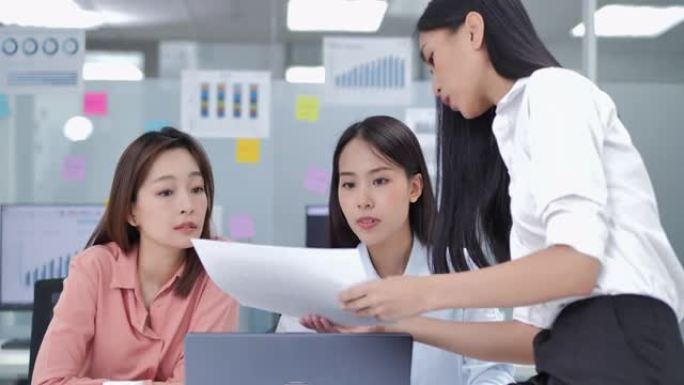 在办公室里，亚洲三位年轻的商业女性自信地使用计算机分析数据，同时谈话并在深夜工作时寻找解决方案。高科