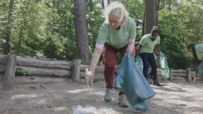 成熟的女人志愿在森林中收集垃圾