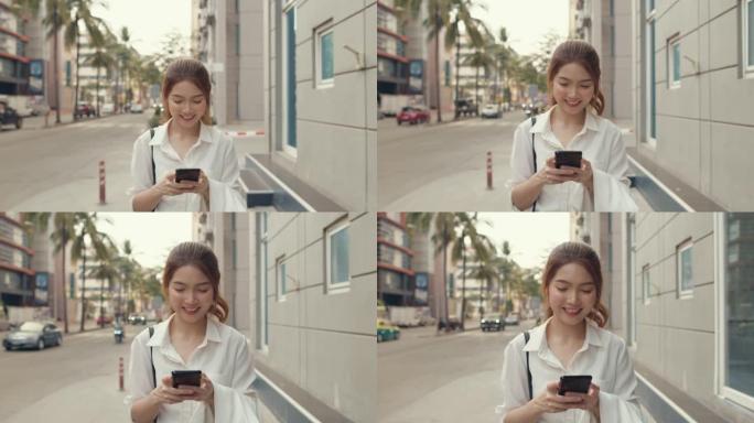 亚洲女商人穿着时尚办公服装，在城市现代城市中独自一人走在户外时，使用智能手机和打字短信。