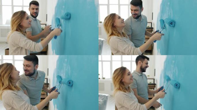 幸福的夫妇，在公寓里用油漆覆盖的鼻子亲吻和大笑画墙