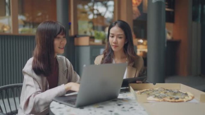 两个亚洲女性商业伙伴在咖啡馆聊天。