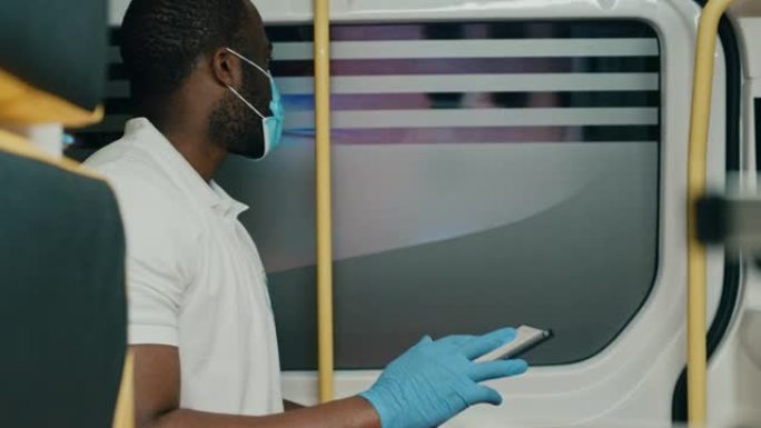 在紧急情况下乘坐救护车时，戴着平板电脑戴口罩的黑人非洲裔美国护理人员。医疗医院外的紧急医疗技术人员。
