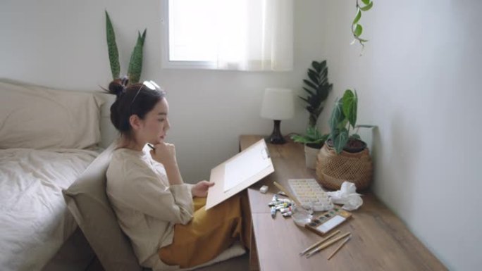 快乐的亚洲女人在家画画。