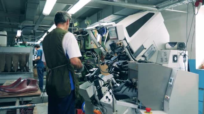 男性工人正在使用机械制造鞋子。鞋类生产设施。
