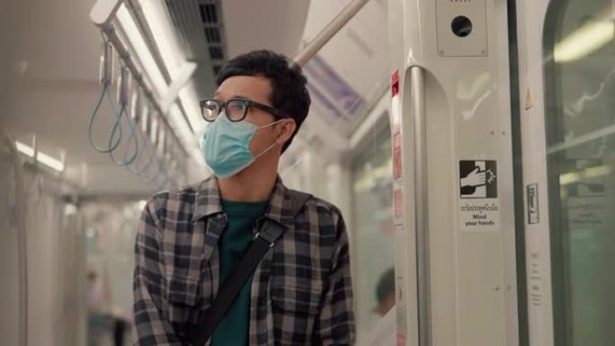 在空气污染期间乘地铁上下班的年轻亚洲男子戴上防护口罩。