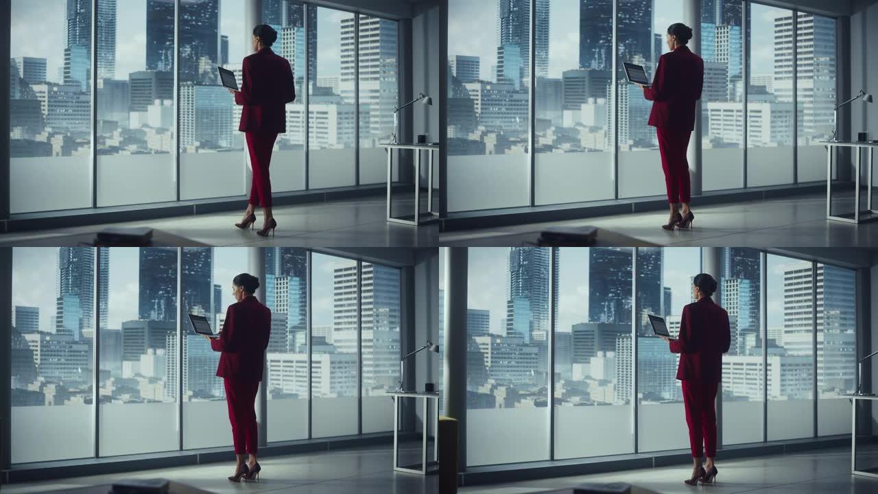 成功的白人女商人站在办公室看着大城市的窗外，使用笔记本电脑。自信的女性管理环境、社会和公司治理