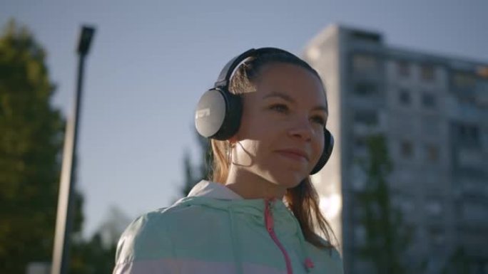 快乐的少女在城市户外用耳机听音乐